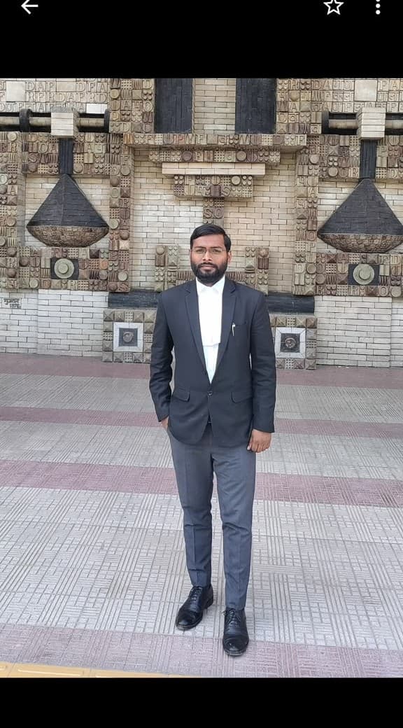 Advocate Shubham Singh in advocate robes before the architectural mural at court complex